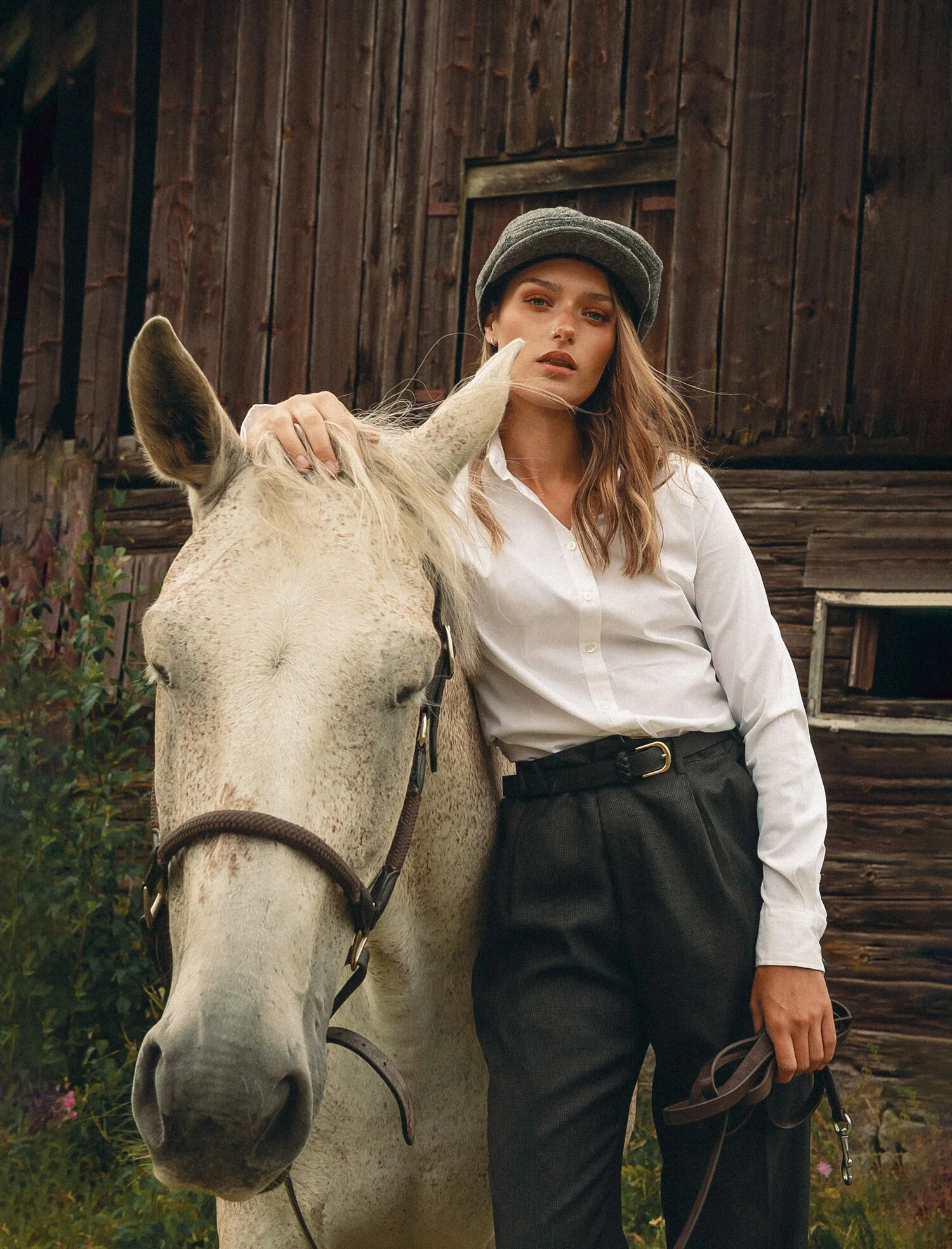 Modellporträtt med häst vid ladugård
