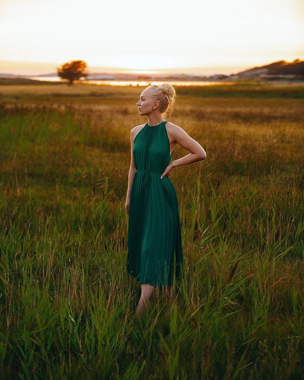 Modefoto grön klänning i fält vid solnedgång